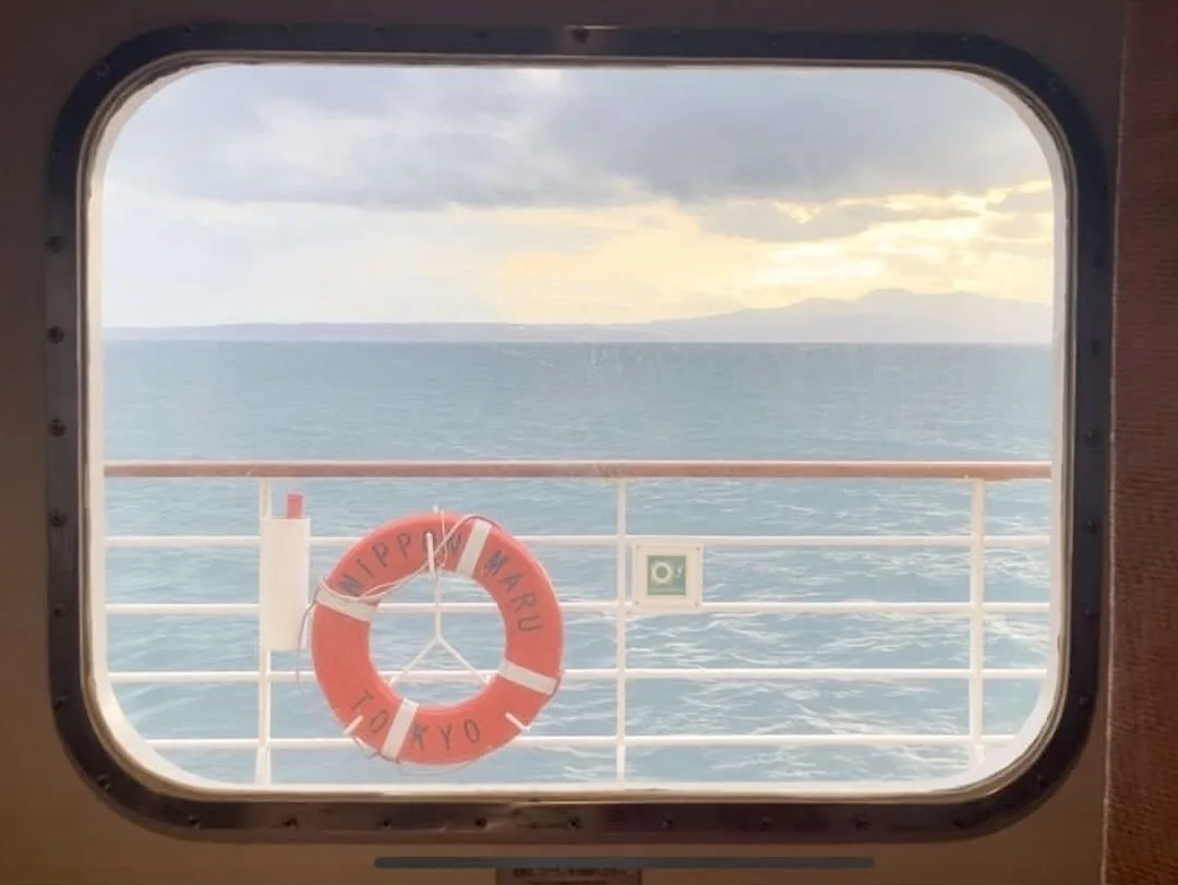 The sea seen through a porthole of the Nippon Maru, with a life ring bearing the ship's name